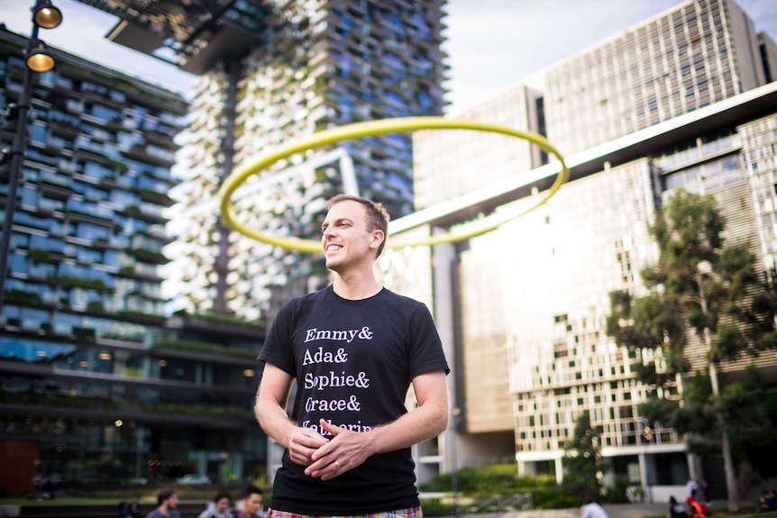 Dr Chris Ferrie stands smiling in a park near Central Station in Sydney CBD.