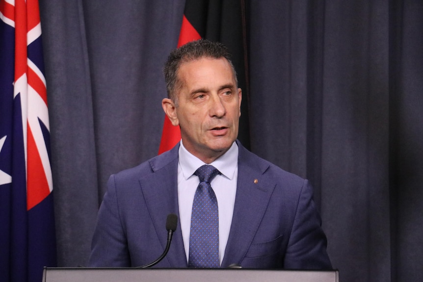 WA police minister Paul Papalia wears a suit while speaking at a lectern.