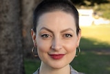 Kimmie Jonceski stares at the camera while standing outside in a grassy area.