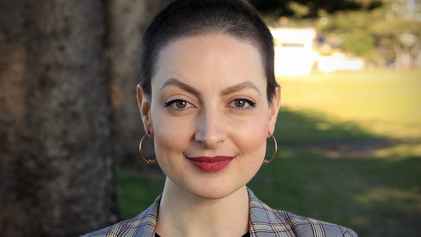 Kimmie Jonceski stares at the camera while standing outside in a grassy area.