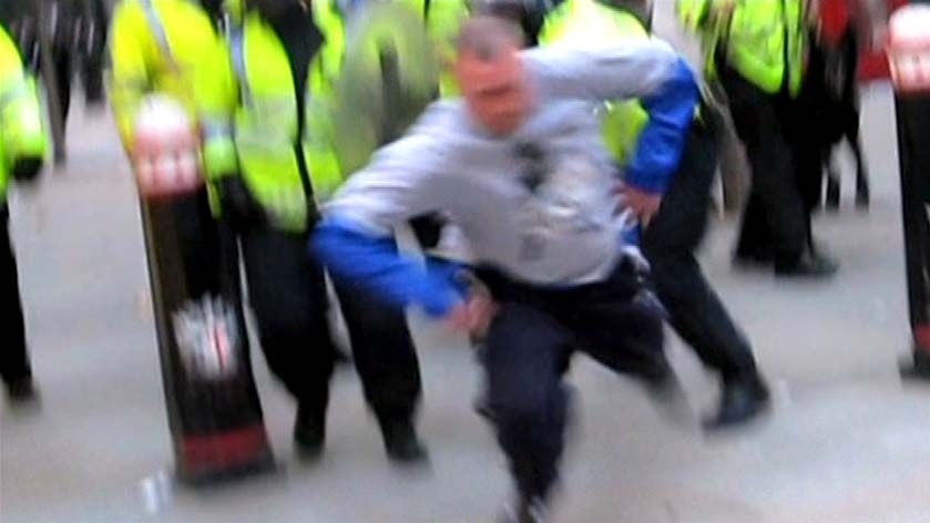 A police officer knocks newspaper seller Ian Tomlinson to the ground