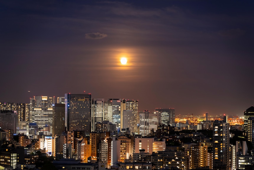 The moon above the Tokyo city skyline at night