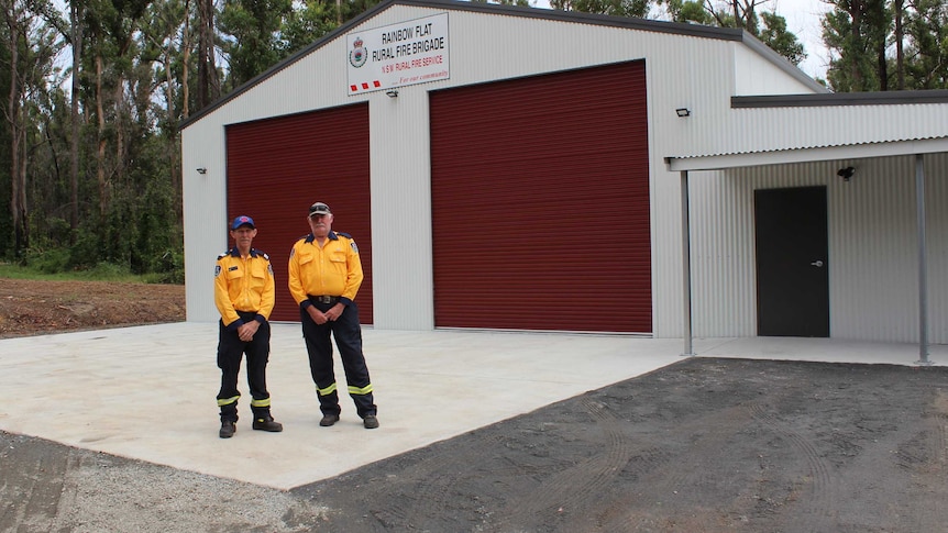 Two men in RFS uniforms outside a new station shed.