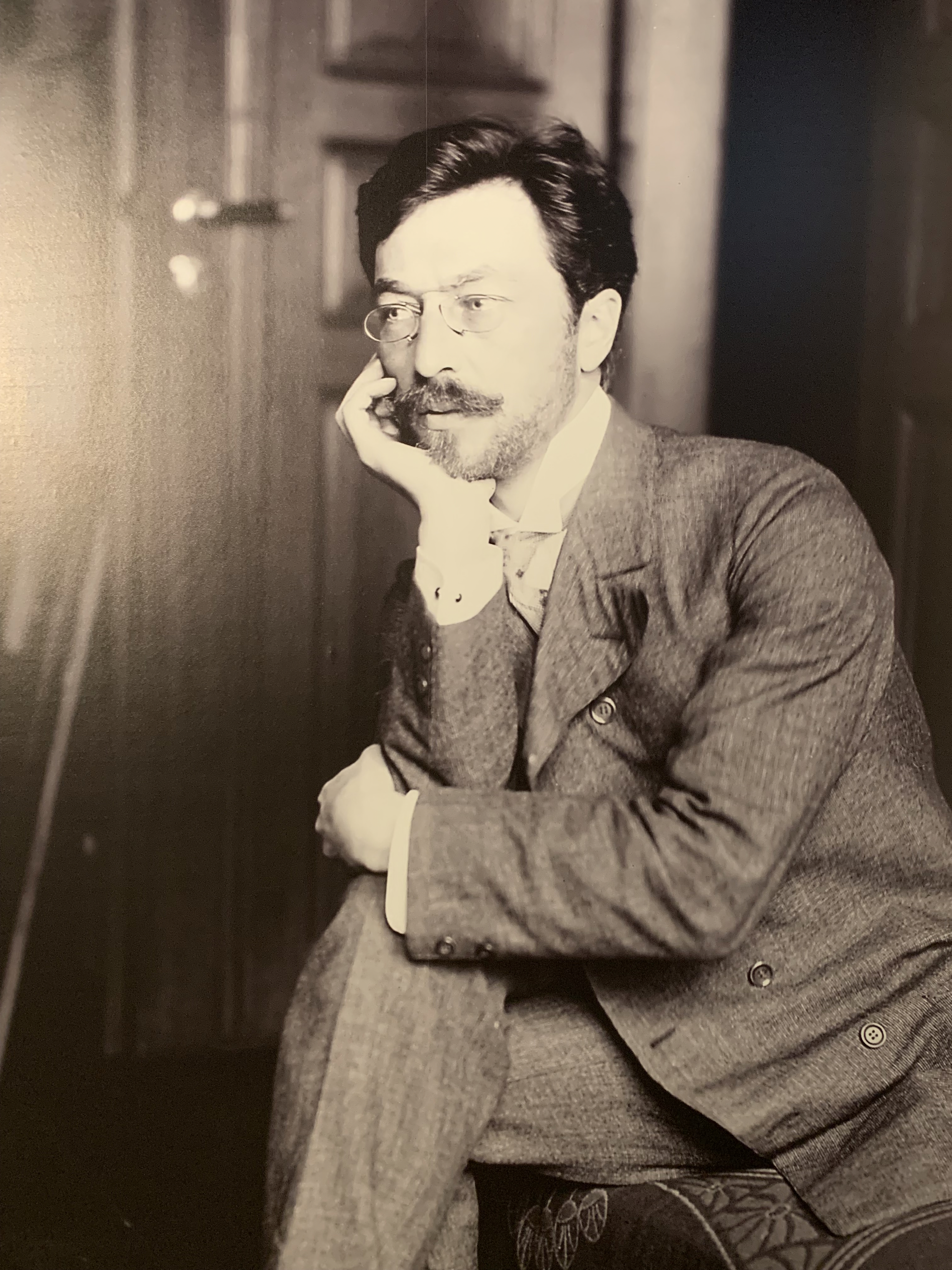 A black and white photo of Vasily Kandinsky taken in 1905 shows him seated, wearing a suit and looking thoughtful.