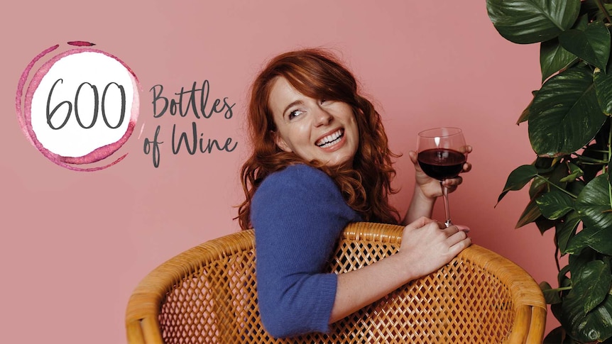 Woman looking back sitting in a wicker chair holding a wine glass