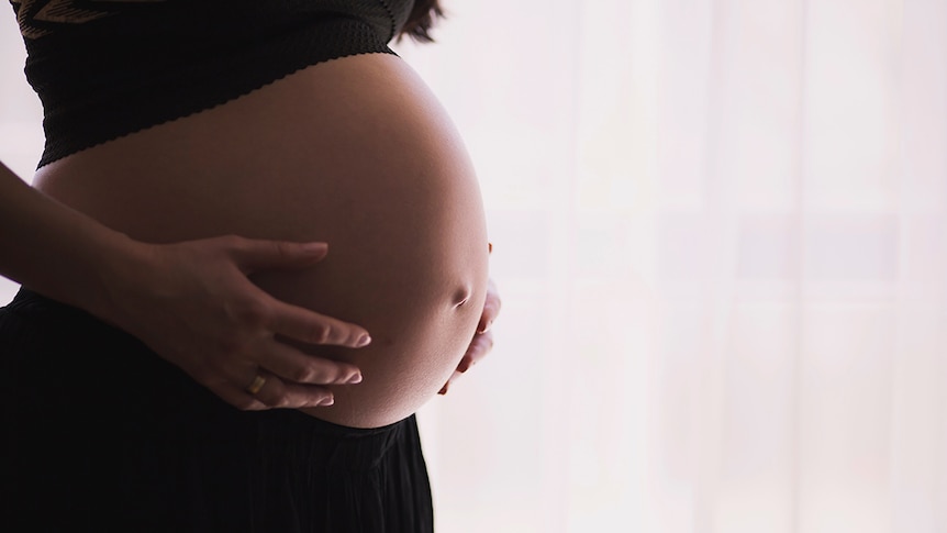 Pregnant woman holding belly.