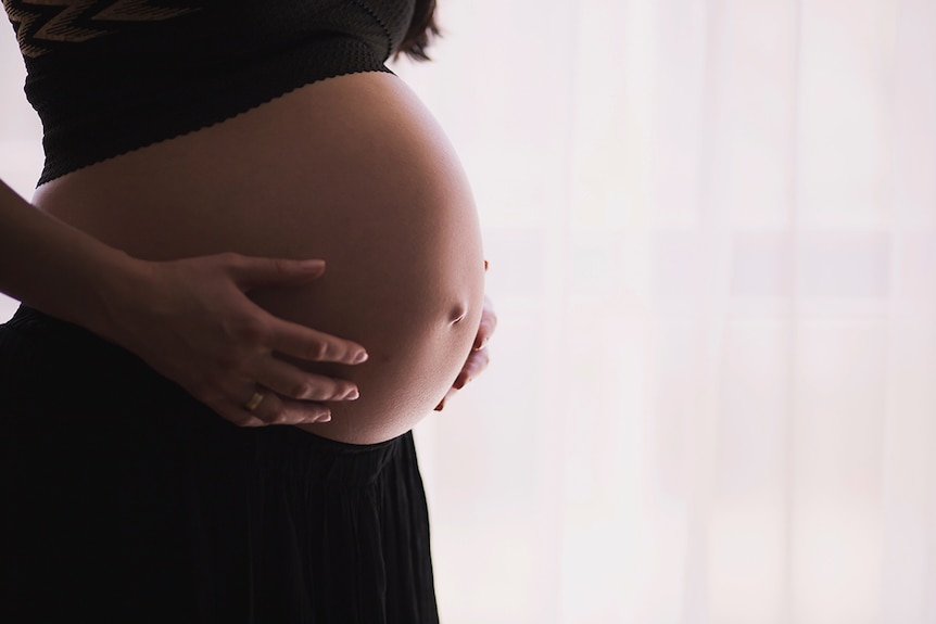 Pregnant woman holding belly.