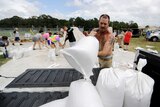 A man lifts a sandbag into an open-trayed ute