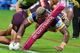A Parramatta Eels NRL player puts the ball down in the corner as he scores a try against Brisbane.