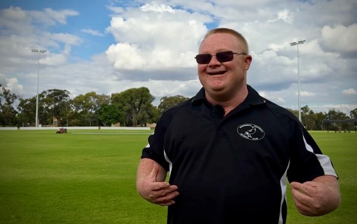 Man wearing Werrimull Football Club shirt standing on oval, smiling