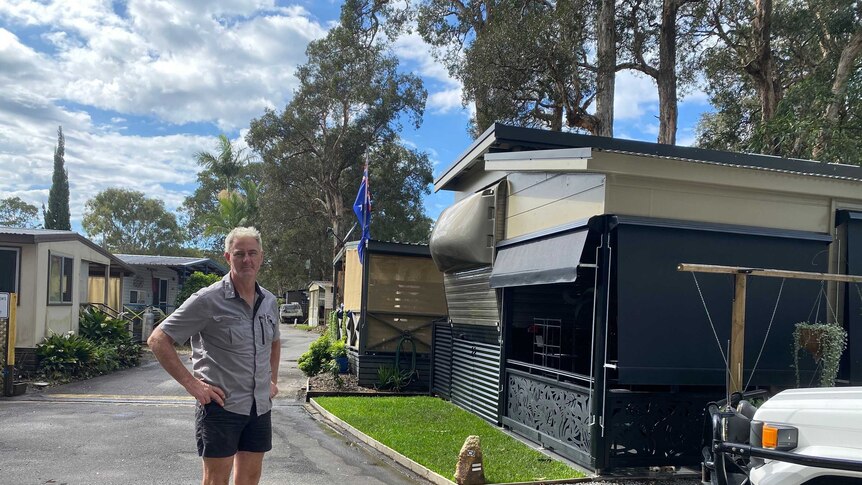 A man stands on the road at a caravan park.