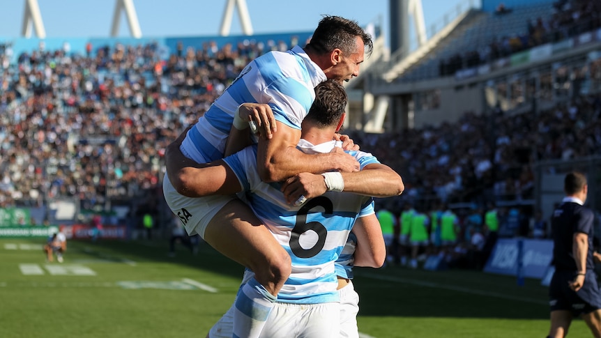 An Argentinian rugby player leaps into the arms of a teammate after a try during an international.