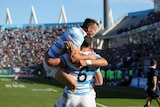 An Argentinian rugby player leaps into the arms of a teammate after a try during an international.