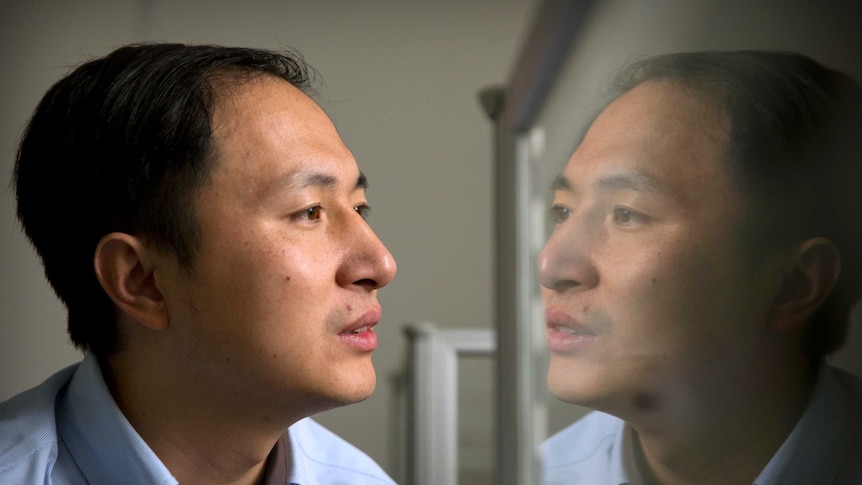 He Jiankui stares at a reflection of himself in a computer screen