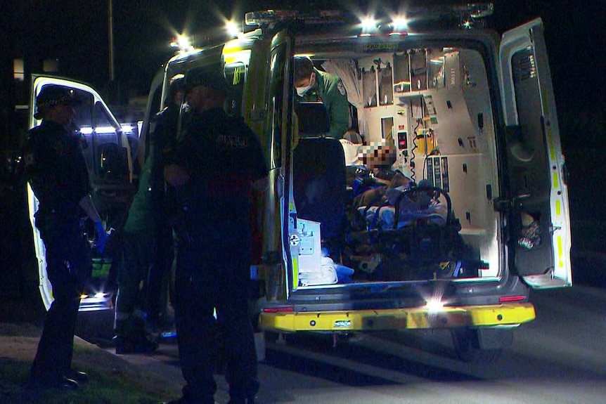 A man in the back of an ambulance with police officers around