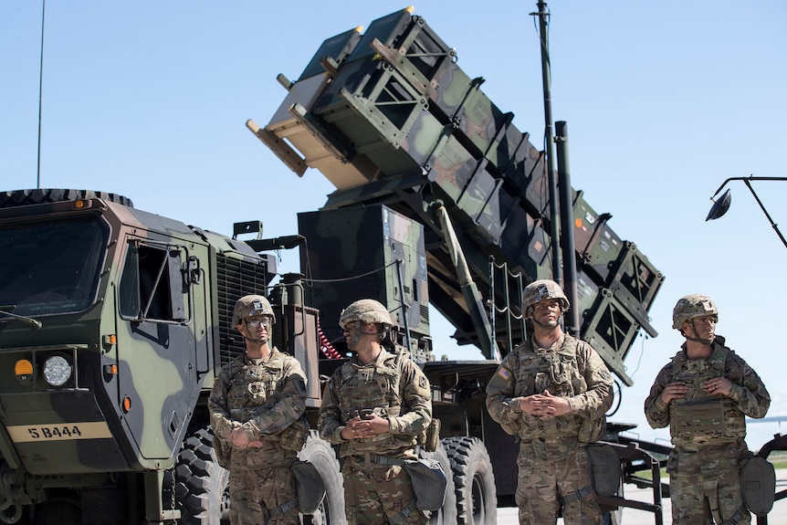 US soldiers stand in front of a Patriot surface-to-air missile battery.