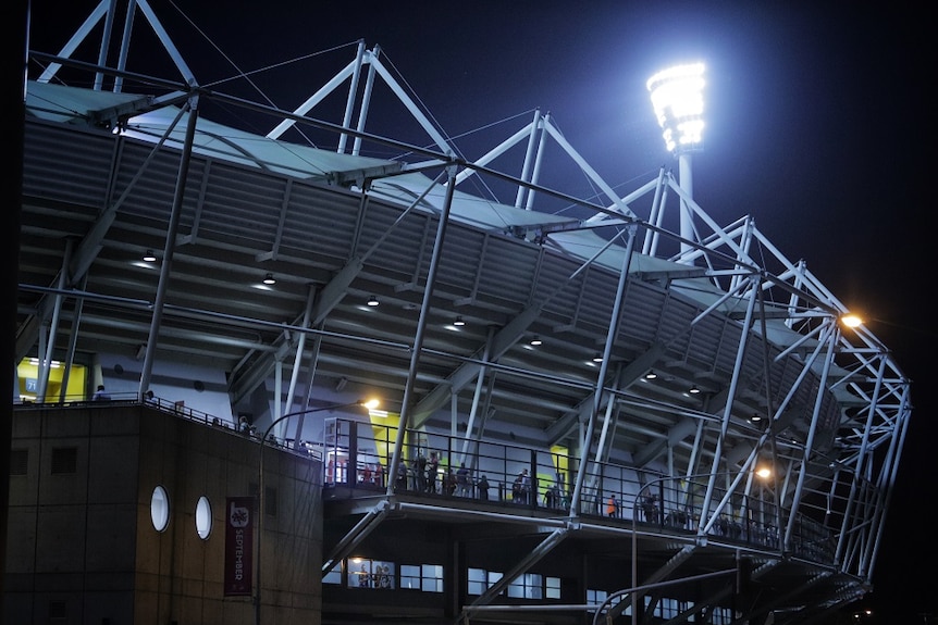 Vue arrière d'un projecteur moderne dans un stade sportif par une nuit sombre.