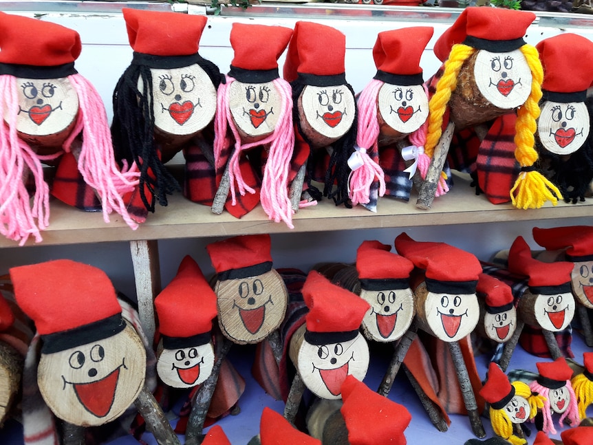 Christmas logs with faces painted on them sit along two shelves.