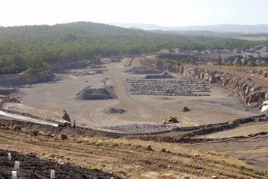A wide picture of a rock quarry surrounded by bushland