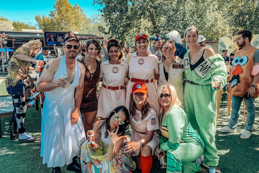 a group of women pose for a photo dressed is baseball costumes.