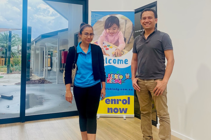 Santika Arzal and her husband stand in front of a sign welcoming people to a new childcare centre