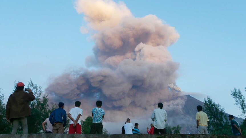 Residents watch as Mayon volcano spews smoke and ash