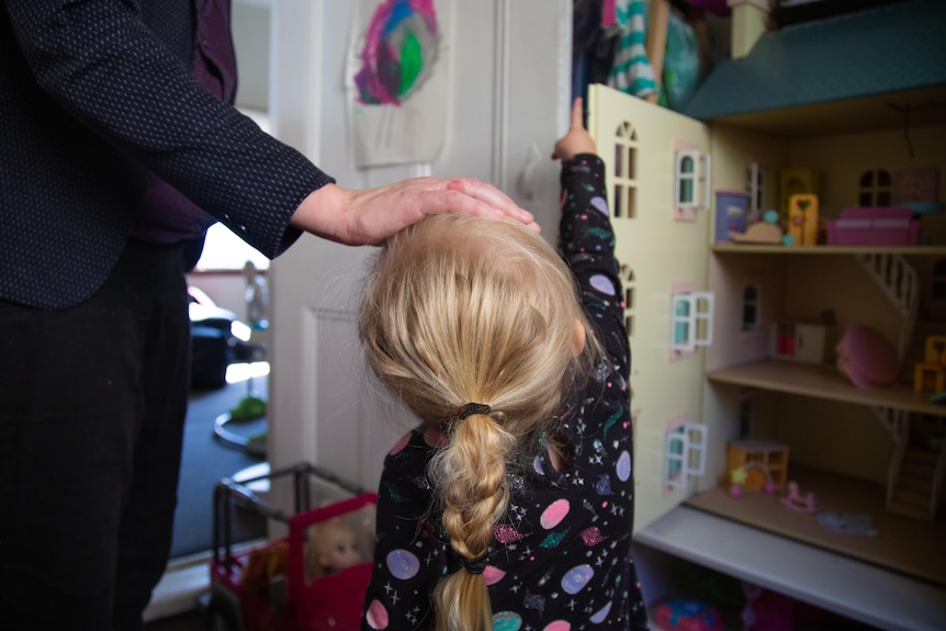 Young girl next to a dollhouse interior