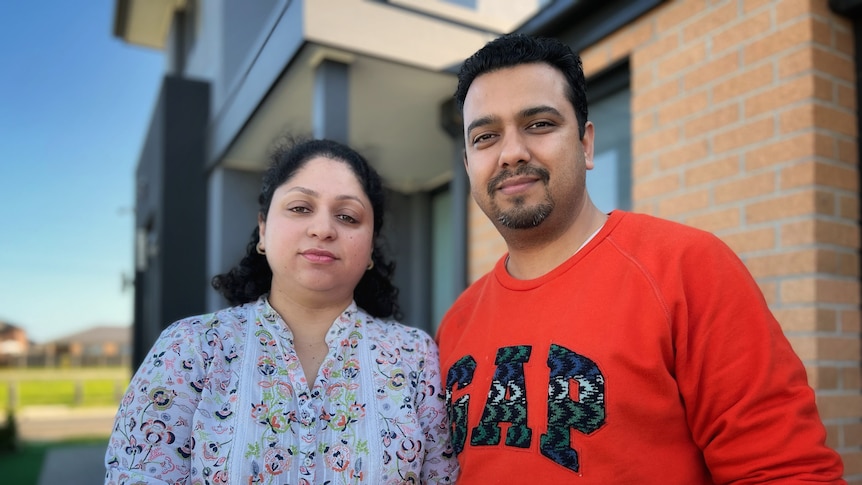 A man and a woman standing in front of a house