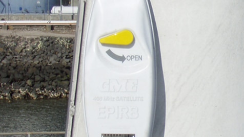 A float free EPIRB hanging on the wall of a boat.