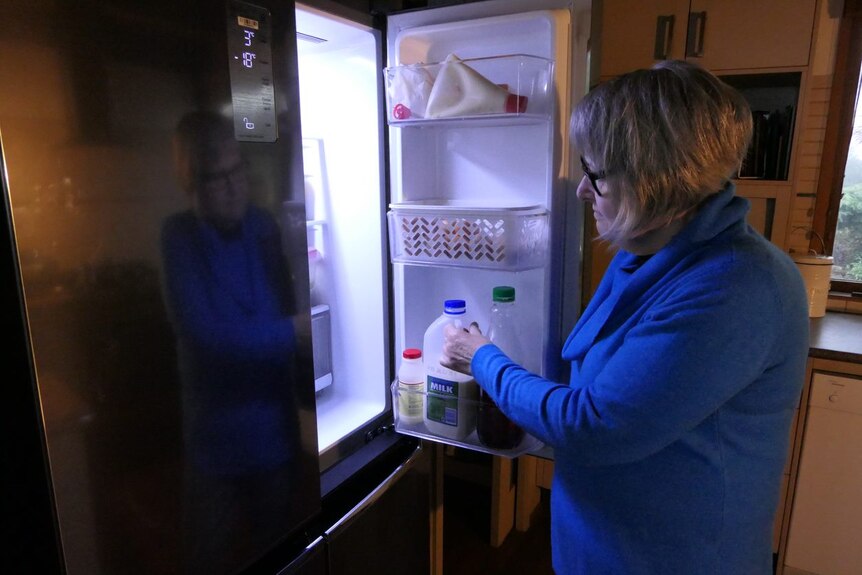 A woman looks inside a fridge.
