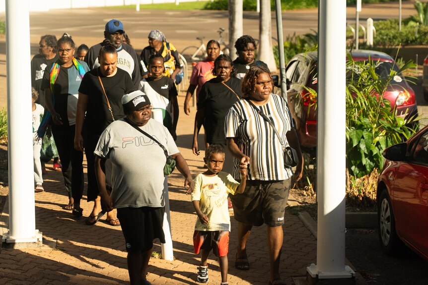 A large Aboriginal family group walk towards Darwin's Supreme Court