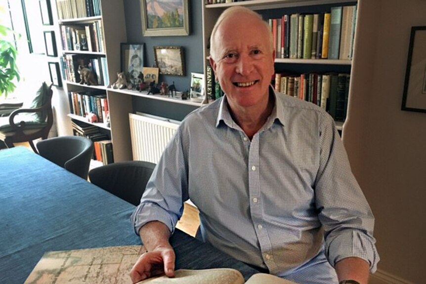 Thomas Kelly sitting in his home, holding a book of his great-grandfather's published letters.