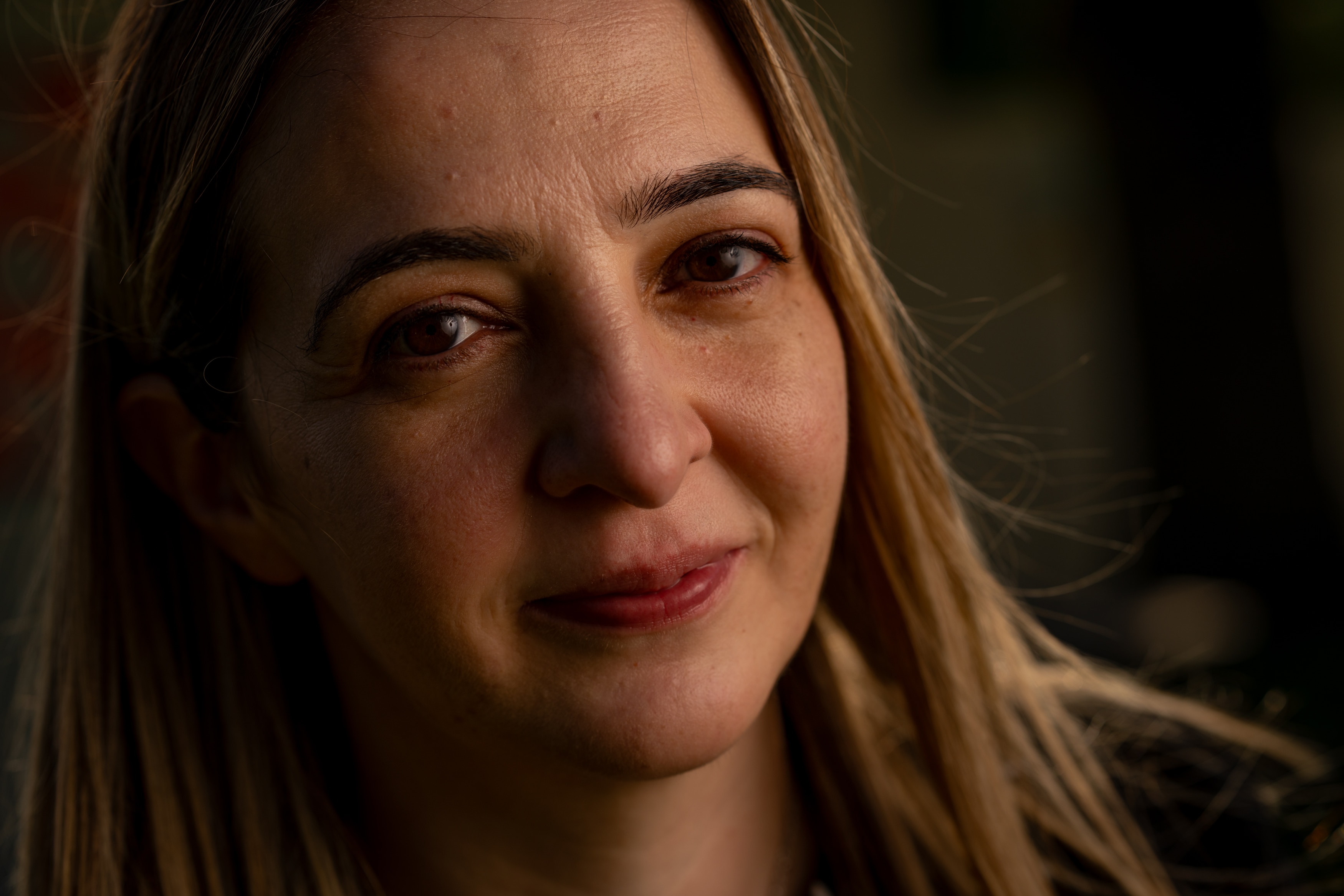 Una mujer aparta la mirada de la cámara y viste un suéter negro.