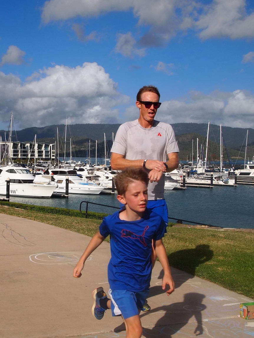 Chris Murphy checks his watch as he runs with his son at Airlie Beach parkrun.