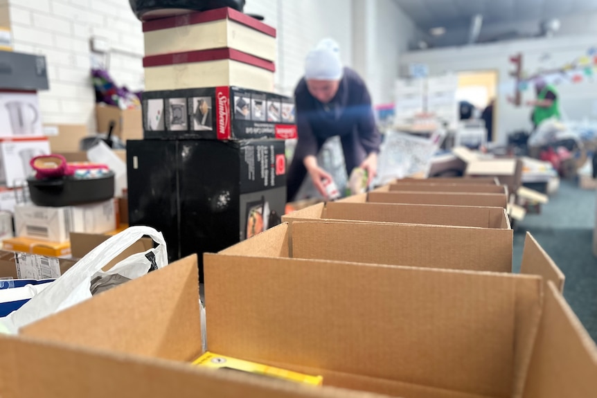 Se ven filas de cajas que un voluntario está llenando. 