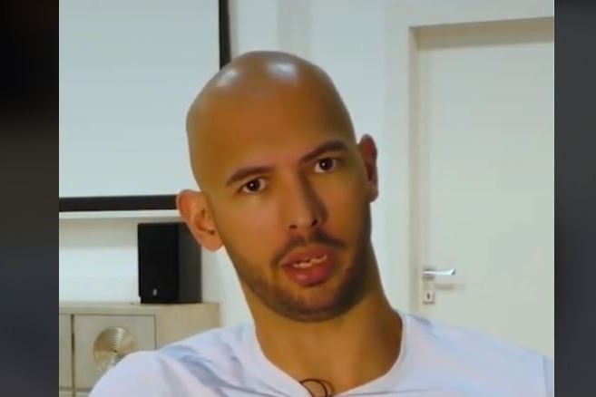 Bald man wearing white tee shirt stares at camera.