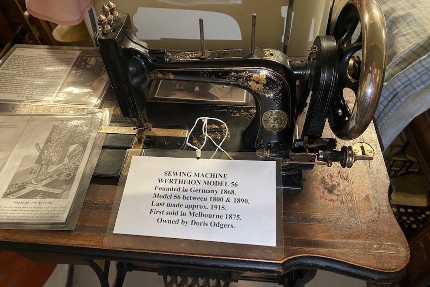 an older table-set sewing machine with a sign explaining what it was and who used it