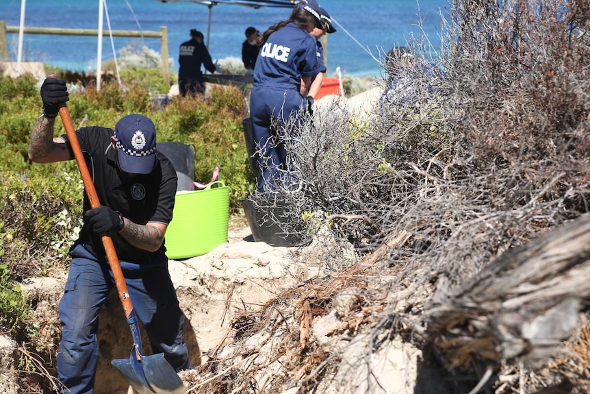 police with shovels search dunes with ocean in the background