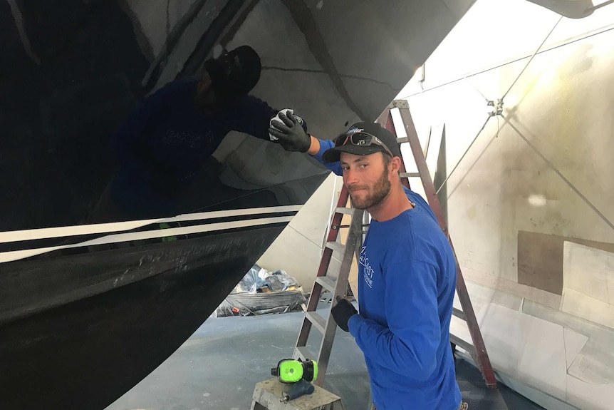 A shipwright washes down a yacht at Midcoast Boatyard & Marine at Newcastle's Wickham Harbour.