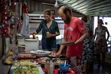 A man and a woman peruse a table full of dishes in a shed