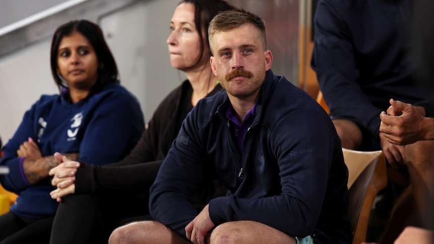 Cameron Munster sits on the sidelines of a Melbourne Storm NRL game after getting injured.