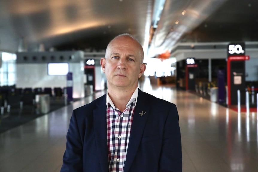 Perth Airport CEO Kevin Brown stands in a deserted Terminal One, wearing a suit and looking serious.