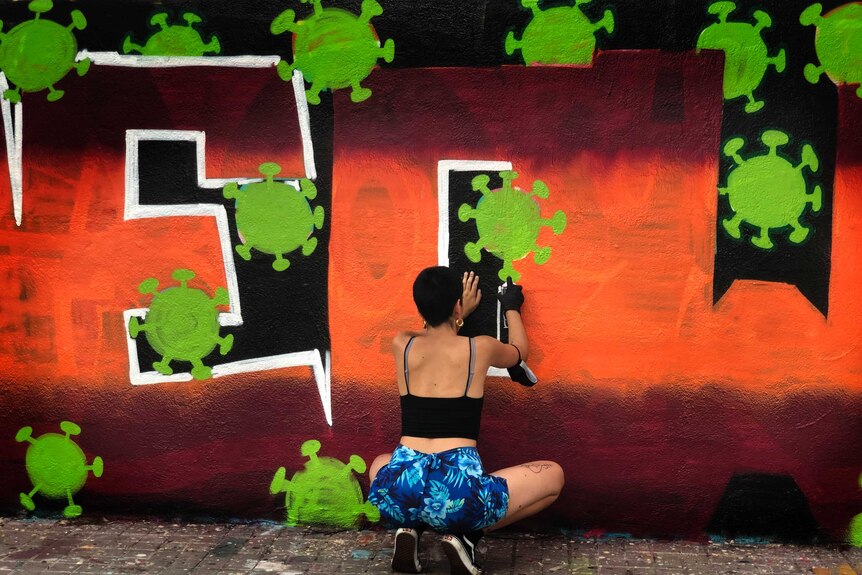 An artist sprays paints a coronavirus-themed mural in Barcelona, Spain.