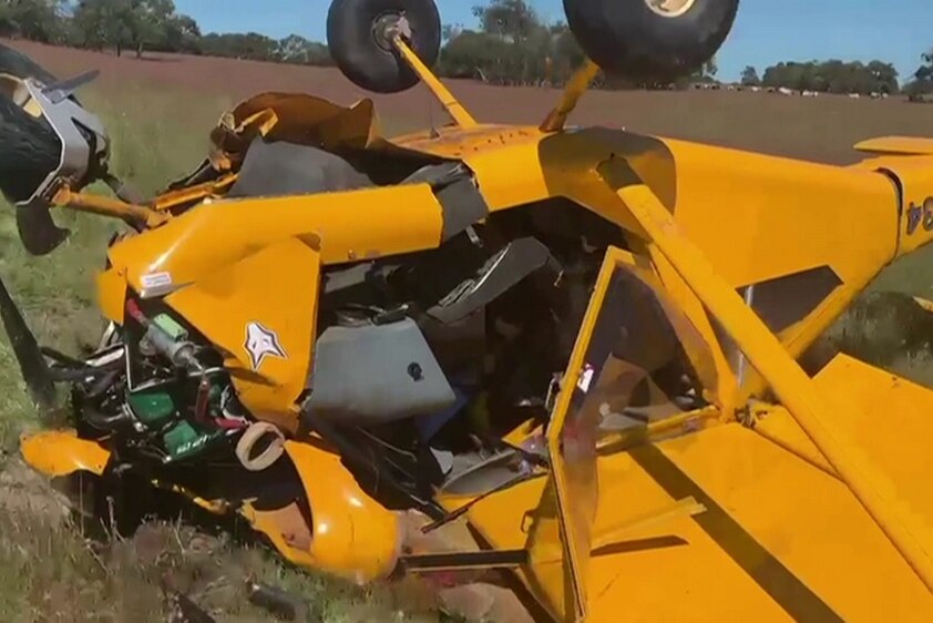 A close shot of a yellow light plane lying on its back in a paddock