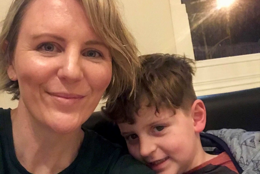 A blond woman sitting indoors with a seven-year-old boy.