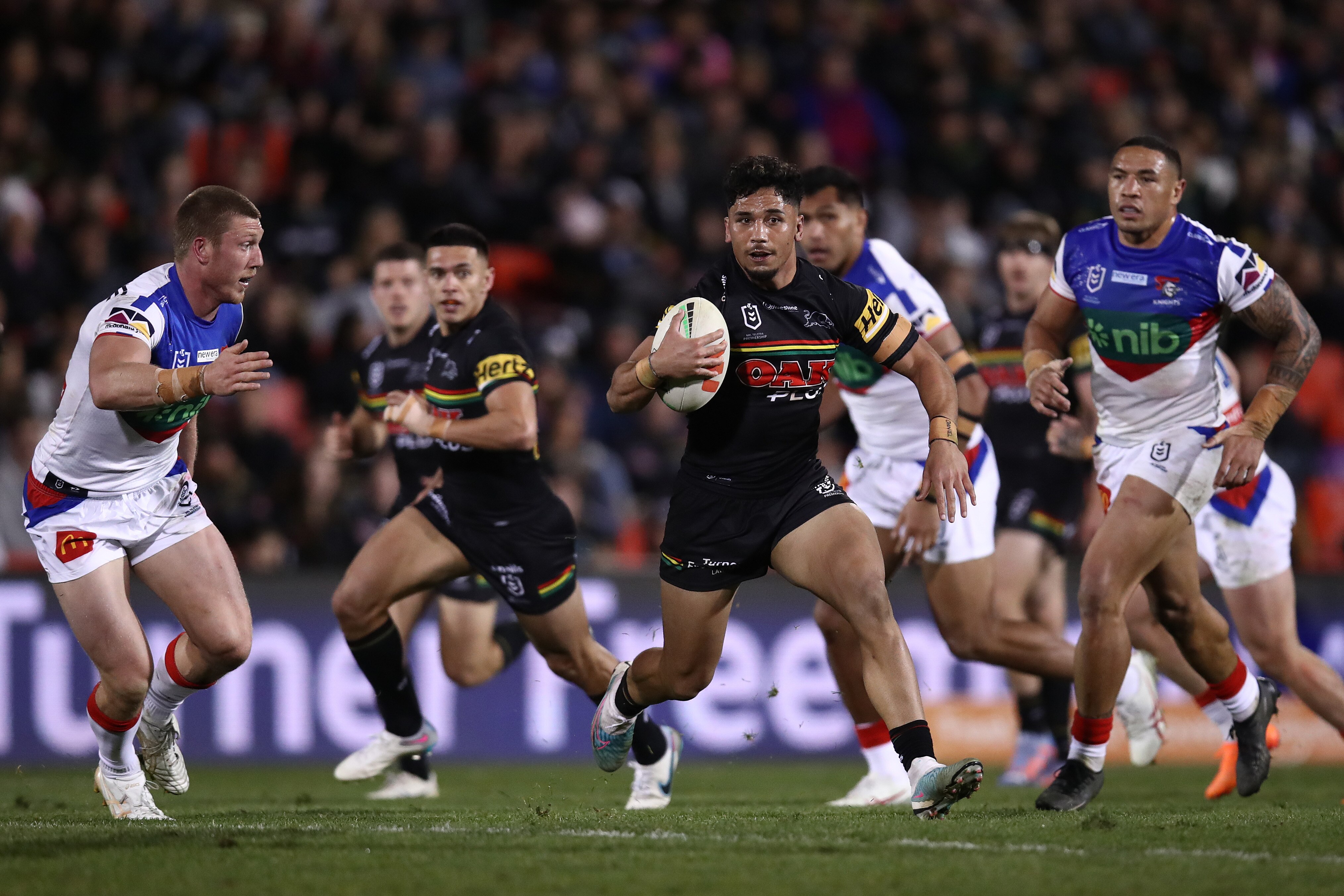 A man runs the ball during an NRL match