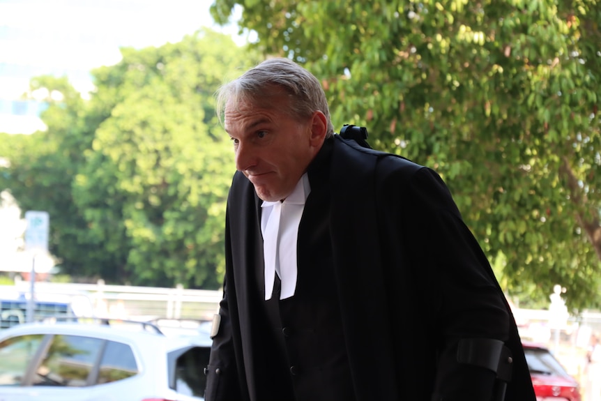 A man in barrister's robes walks out of a carpark