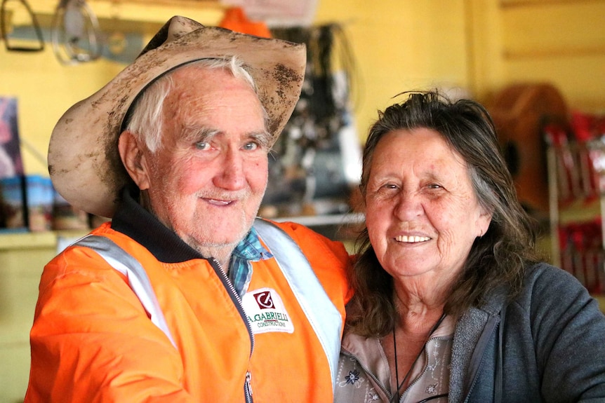 Lester Cain and wife Val smile at the camera, Lester is wearing a battered old hat.