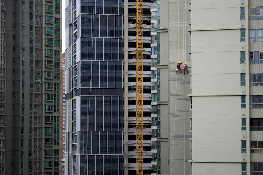 Workers paint a residential building in Shanghai