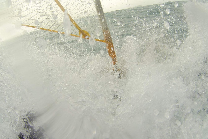 Waves crash over Malcolm Skelton as he guides his kayak through gale force winds and deep ocean swells